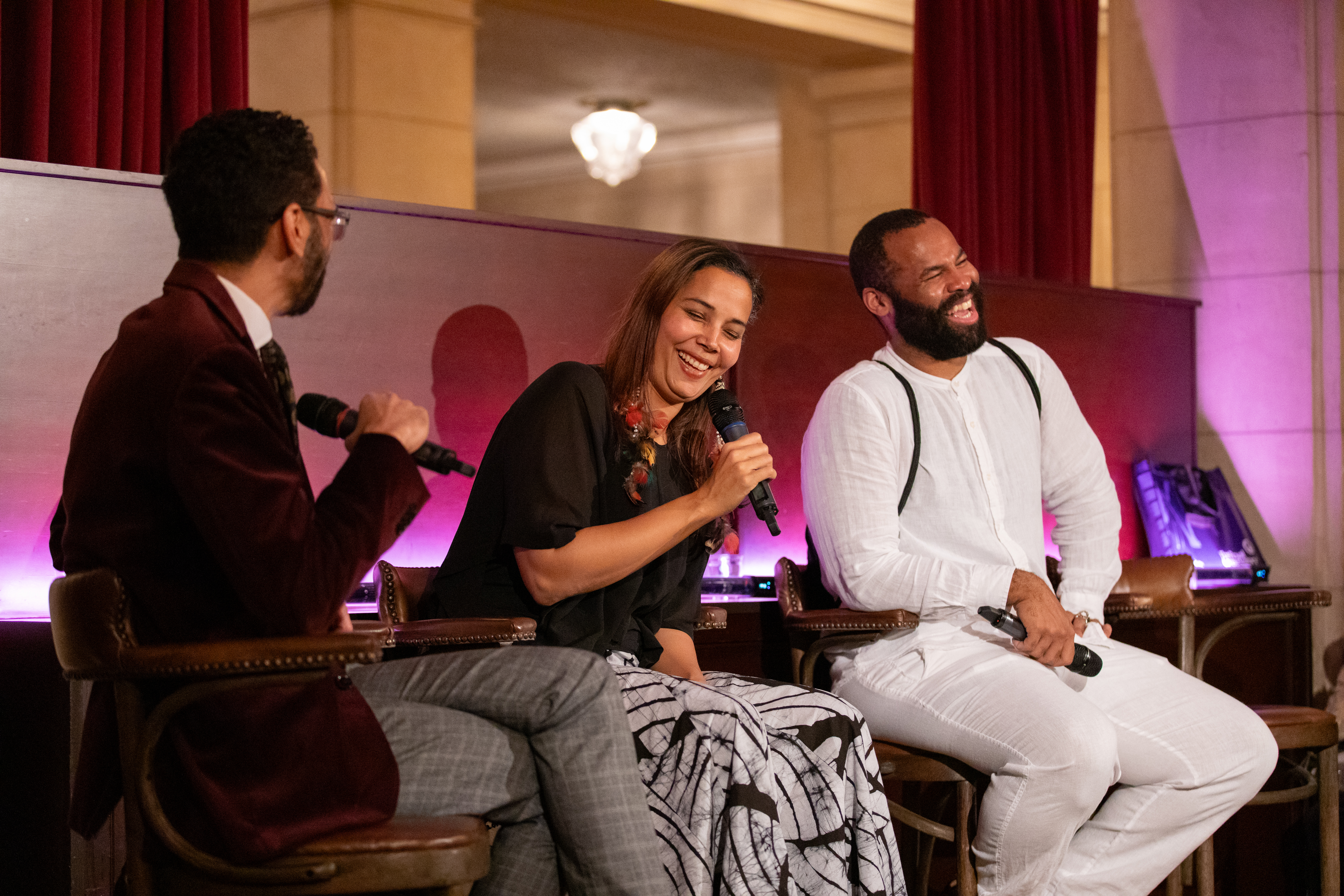 people sitting on stools with mics laughing
